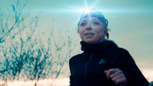 Woman jogging in the dark with a headlamp in sport Film Production